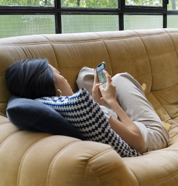 woman laying on sofa scrolling on social media